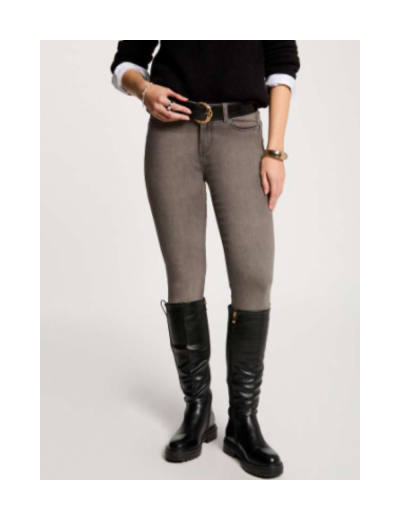 Calças justas cinza claro, cinto preto, botas pretas altas, roupa preta e branca