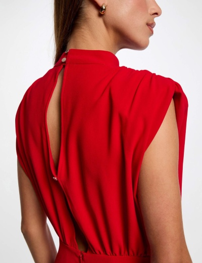 Vestido vermelho com costas abertas e botões prateados, usado por mulher