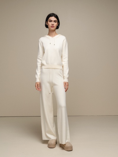 Conjunto feminino de malha creme com hoodie e calças largas em ambiente neutro