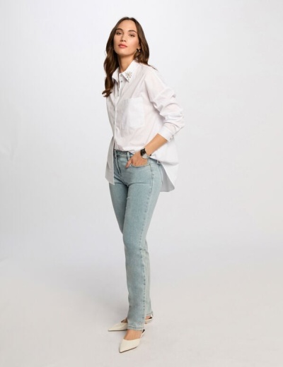 Mulher com camisa branca, calças de ganga azul claro e sapatos brancos