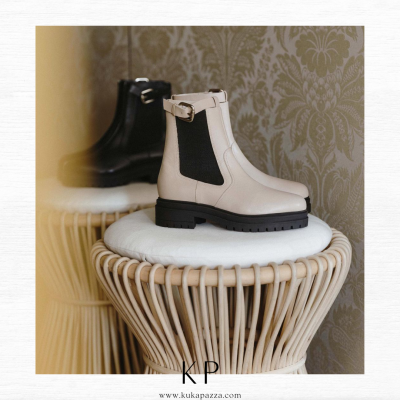 Botas Chelsea em branco e preto sobre puf de vime com almofada branca