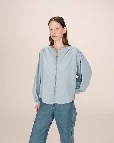 Mulher veste blusa azul clara de tecido com mangas bufantes e calças de ganga azul