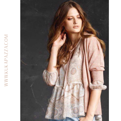 Mulher com blusa clara estampada e casaco rosa claro