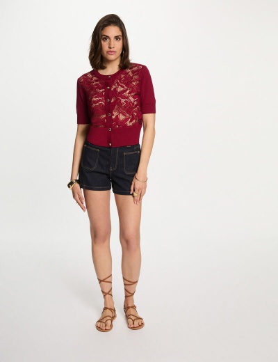 Mulher a usar camisola vermelha em renda, calções de ganga escura e sandálias castanhas de tiras finas