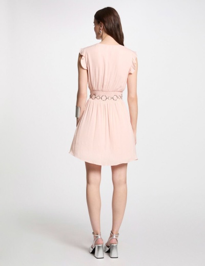 Vestido rosa claro curto visto de costas com cinto de argolas e sapatos prateados.