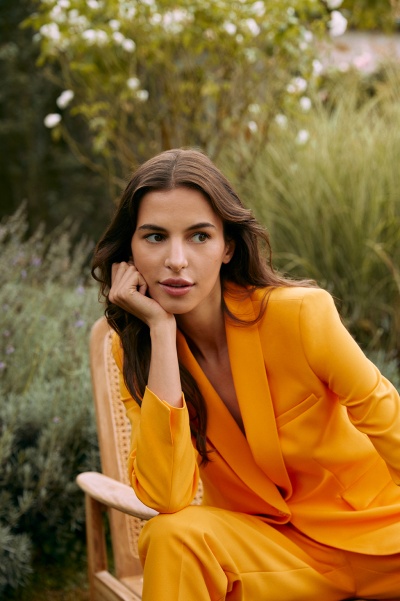 Mulher em fato amarelo sentada em cadeira de madeira ao ar livre