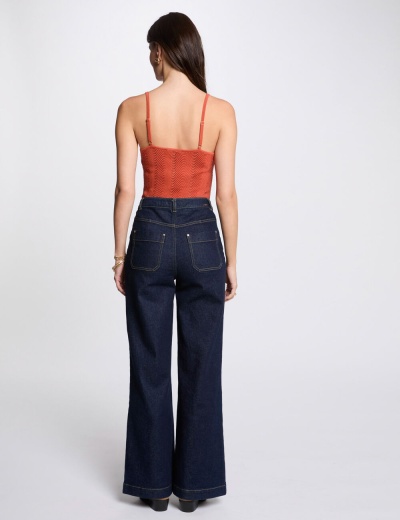 Modelo de costas vestindo top cropped vermelho texturizado e calças de ganga azul escuro largas