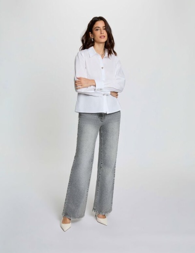 Mulher com camisa branca e calças de ganga cinza