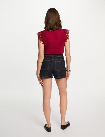 Mulher de costas com top vermelho e calções de ganga escuros