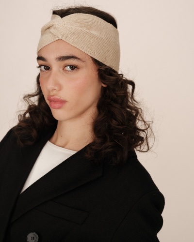 Mulher com faixa de cabeça bege de tecido e casaco preto