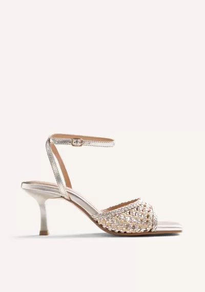 Sandália feminina de salto médio prateado com tira fina no tornozelo e parte da frente trançada.