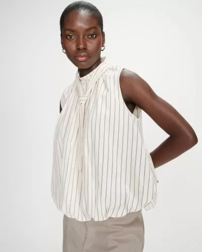 Blusa branca às riscas verticais pretas com nó ao pescoço, usada por mulher em fundo branco.