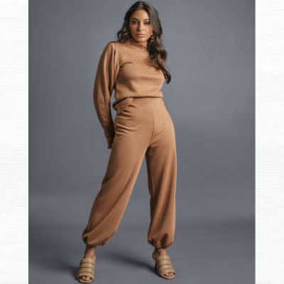 Conjunto de malha castanho com camisola de gola alta e calças largas em fundo cinzento