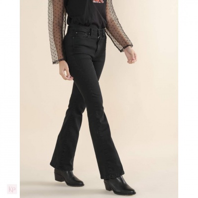 Calças pretas flare em modelo com camisa preta e botas pretas