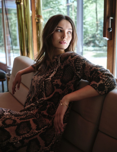 Mulher sentada no sofá com vestido de padrão de pele de cobra