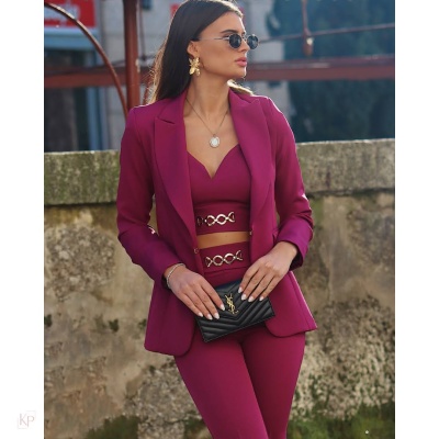 Conjunto feminino bordô com blazer, calças e top com detalhes dourados, mala preta acolchoada, acessórios dourados, em ambiente exterior