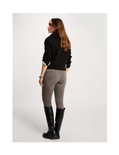 Mulher de casaco preto, calças cinza e botas pretas vista de costas