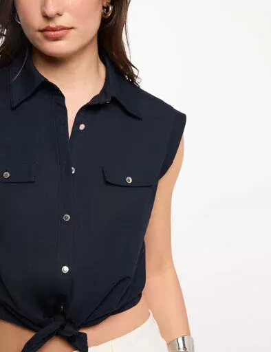 Camisa sem mangas azul escura com botões e bolsos frontais, atada em nó