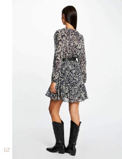 Mulher vista de costas usando vestido floral preto e branco com cinto preto e botas pretas