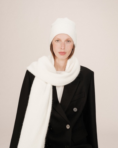 Mulher a usar gorro e cachecol brancos felpudos e casaco preto com botões cinzentos