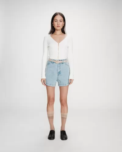 Mulher com camisola branca, calções de ganga, cinto bege, meias transparentes e sapatos pretos