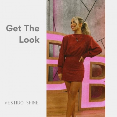 Mulher com vestido vermelho de malha em ambiente interior com parede cinzenta e letras decorativas rosa