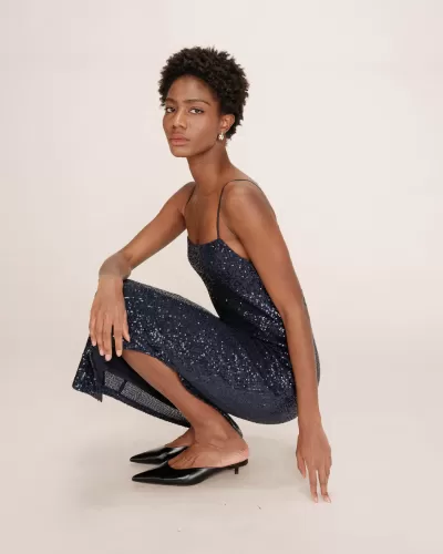 Mulher vestindo vestido azul escuro com lantejoulas e sapatos pretos