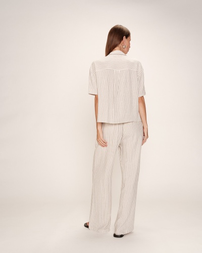 Conjunto feminino creme às riscas visto de costas com fundo neutro