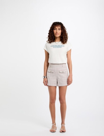 Mulher com t-shirt branca e calções cinza com padrão aos quadrados