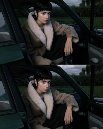 Mulher com casaco bege de pelo branco sentada em carro verde.