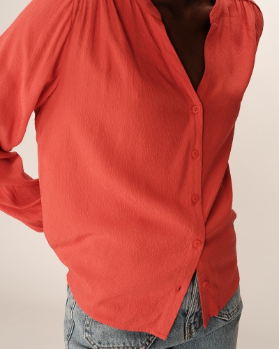 Camisa feminina coral texturizada com botões e calças de ganga azuis