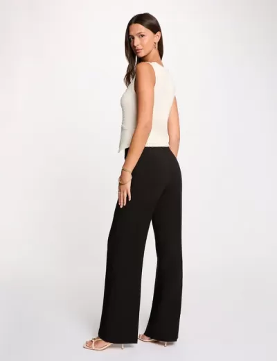 Mulher com top branco e calças pretas largas