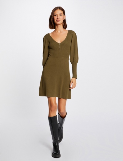 Vestido verde-oliva de malha com mangas compridas usado com botas pretas.