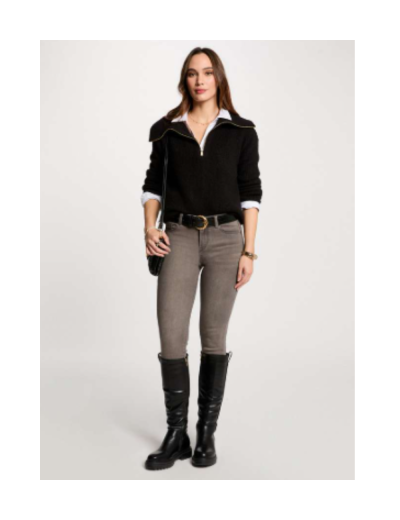 Mulher com camisola preta, calças cinza, botas pretas e bolsa preta