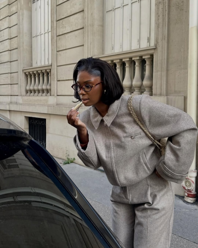Mulher a aplicar batom numa rua com edifício de pedra ao fundo