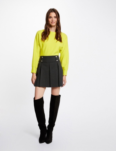 Mulher a usar camisola amarela, saia preta e botas pretas