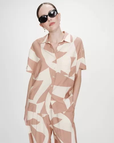 Conjunto de roupa bege e creme com padrão abstrato, camisa e calças, mulher com óculos escuros.