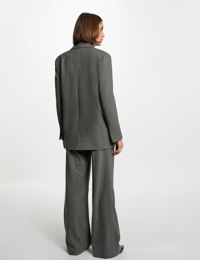 Conjunto de blazer e calças largas cinzentas em tecido texturado, modelo vista de costas.