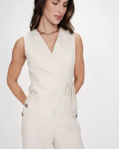 Colete feminino bege claro sem mangas com laço lateral e calças bege claras com botões nas laterais