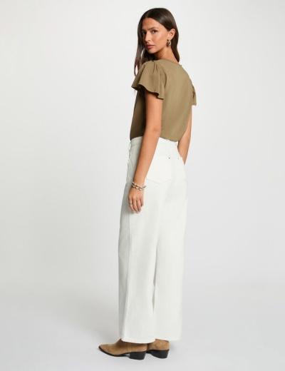 Mulher com blusa kaki e calças brancas largas vista de costas em fundo branco