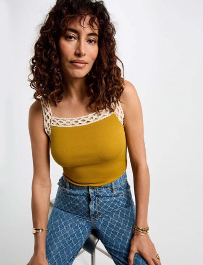 Top amarelo mostarda com alças de renda e jeans azuis com padrão xadrez