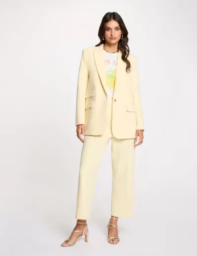 Conjunto feminino amarelo claro com blazer, calças pantalonas, t-shirt branca com estampa e sandálias de salto