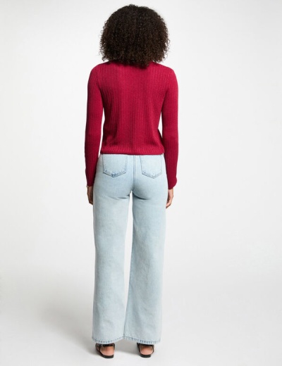 Pessoa de costas com camisola vermelha e calças de ganga azul clara