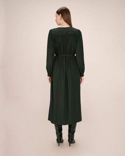 Vestido comprido verde escuro de costas com botas pretas