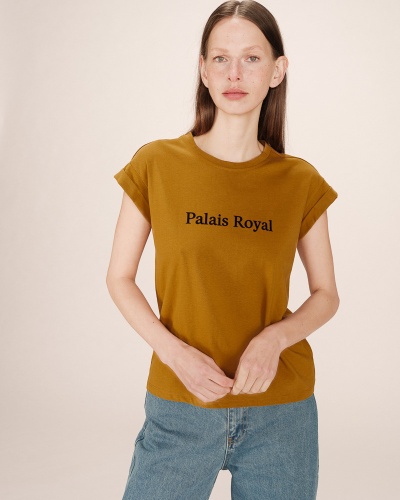 Mulher com t-shirt amarelo mostarda com texto Preto 'Palais Royal' e calças de ganga azuis