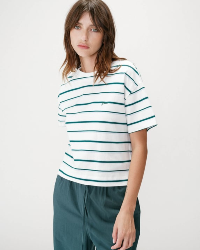 T-shirt branca com riscas verdes e calças verdes escuras em modelo feminina.