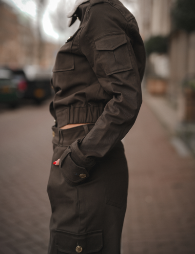 Roupa castanha escura com camisa e saia com bolsos laterais numa rua urbana.