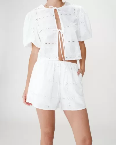 Conjunto de verão branco feminino com camisa curta e calções, padrão perfurado, em fundo neutro