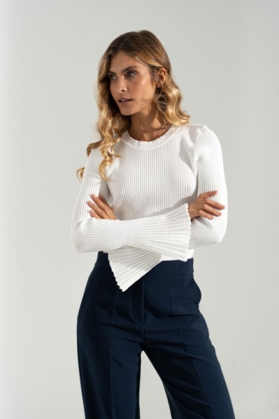 Mulher com camisola branca de malha canelada e calças azuis escuras