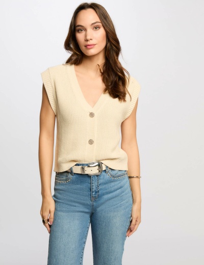 Camisola de malha bege com botões grandes e calças de ganga azul claro.